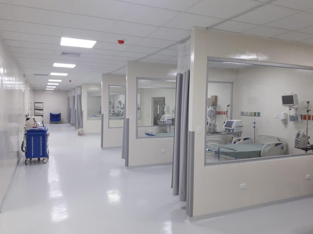 Unidad de cuidados intensivos con cubículos acristalados, ventiladores y monitores.
